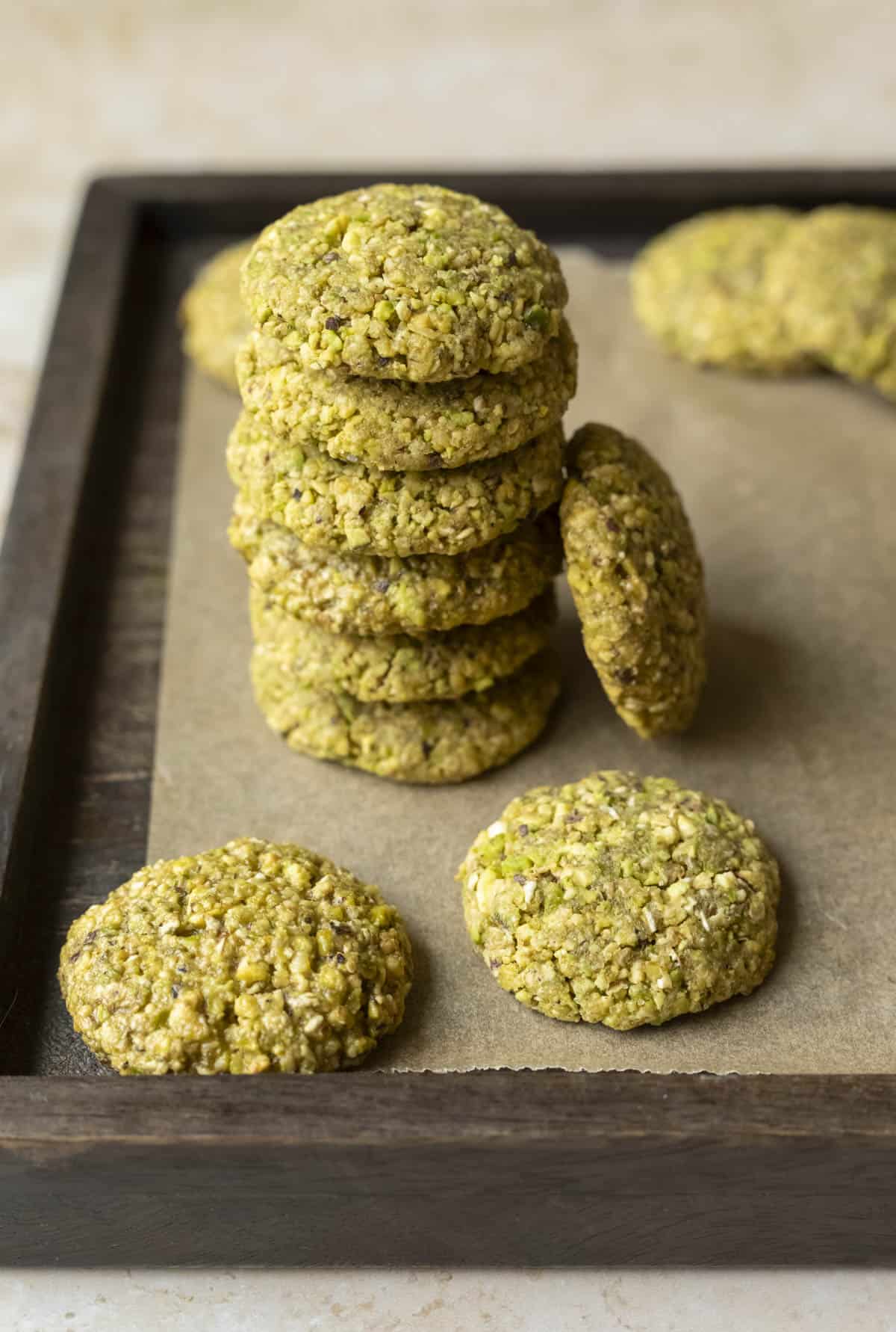A stack of chunky 5-ingredient pistachio cookies on a wood serving board.