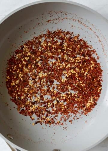 Toasting red chile flakes in a pan.
