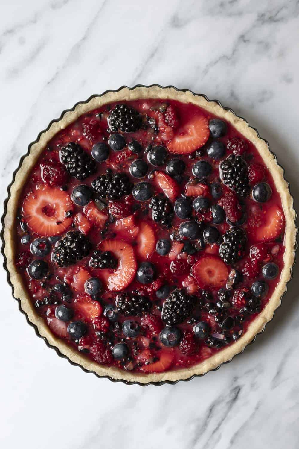 Wild berry filling poured into a tart crust, ready to be baked.
