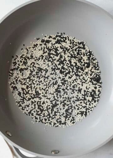 Toasting black and white sesame seeds in a pan.
