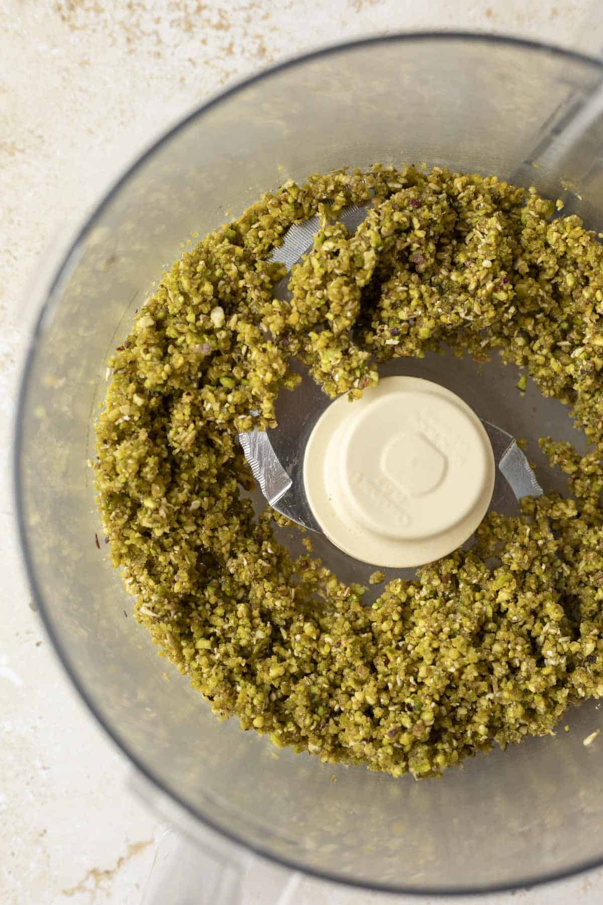 Inside the food processor after adding the maple syrup and vanilla to the nut mixture.