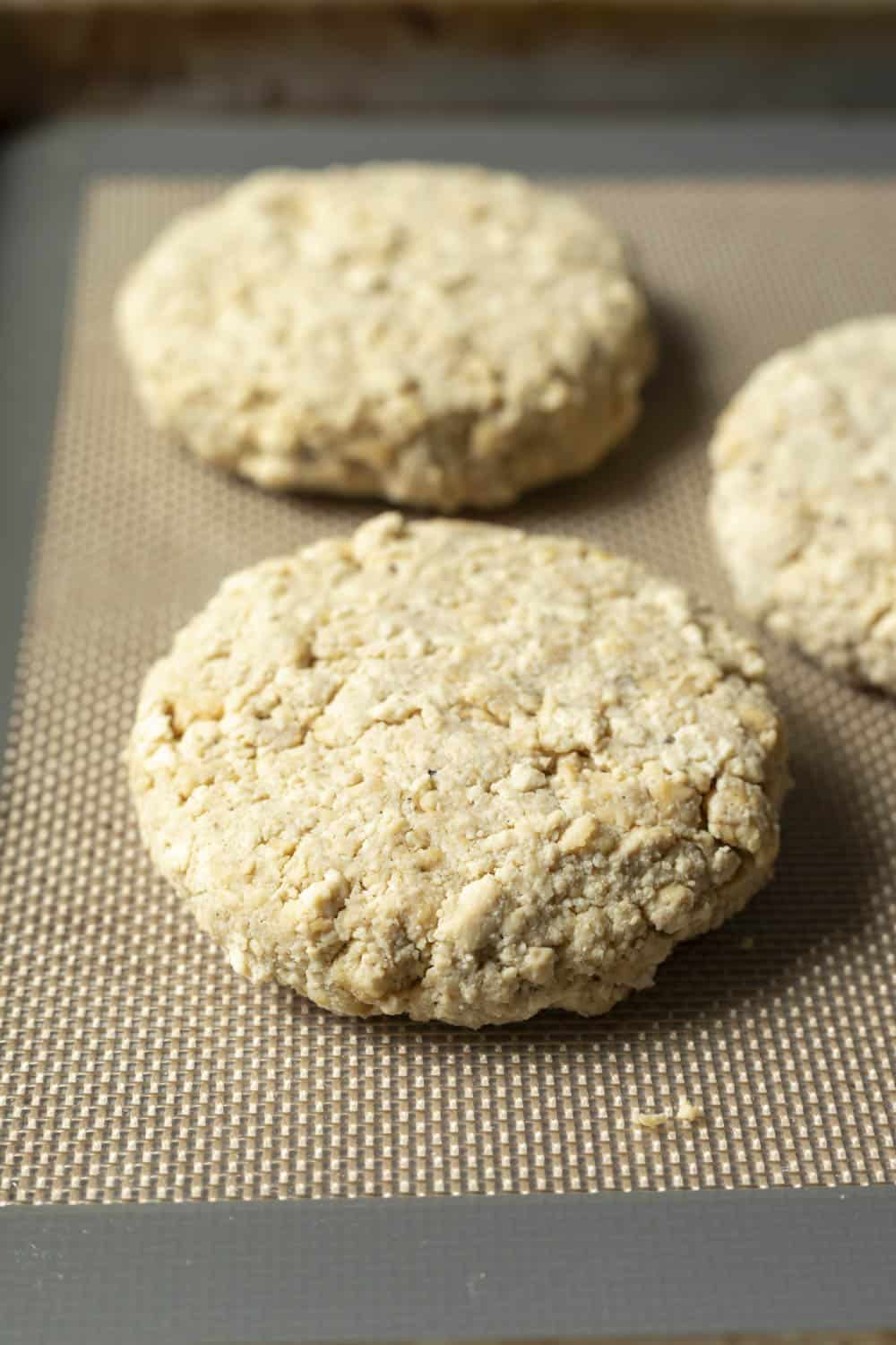 Four tofu patties on a baking sheet.