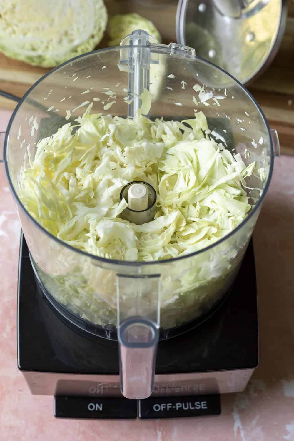 Using a food processor to shred green cabbage.