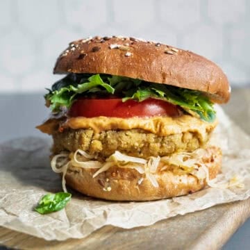 Tofu burger on a bun with mustard, kraut, lettuce, and tomato.
