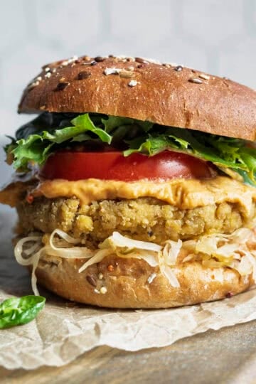 Tofu burger on a bun with mustard, kraut, lettuce, and tomato.