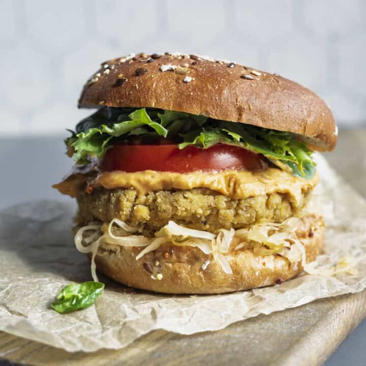Tofu burger on a bun with mustard, kraut, lettuce, and tomato.