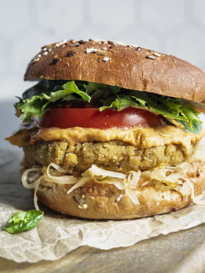 Tofu burger on a bun with mustard, kraut, lettuce, and tomato.