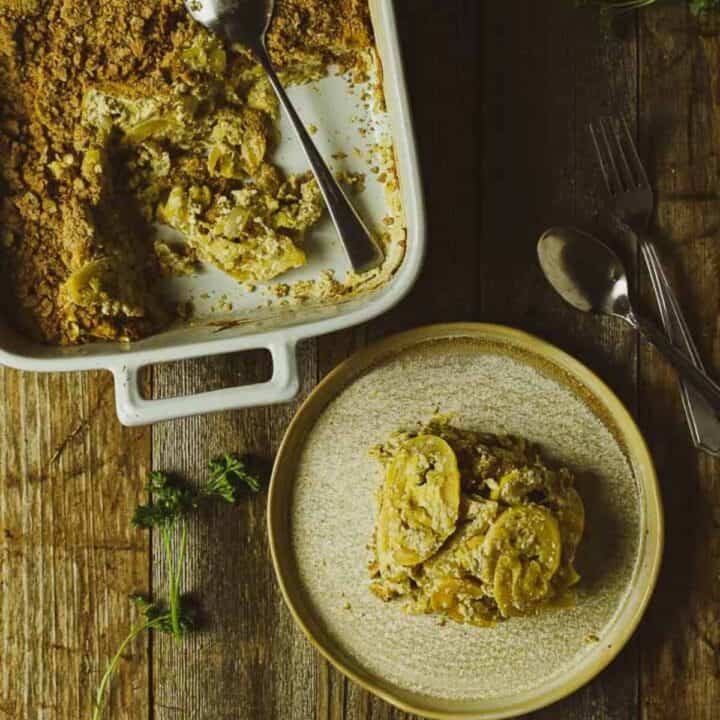 A serving of squash casserole on a plate with the whole dish nearby.