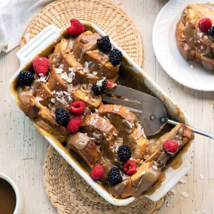 A saucy vegan french toast casserole topped with fresh berries and coconut.