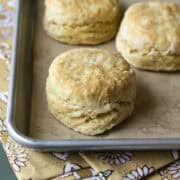Three tall and flaky vegan biscuits on a baking sheet.