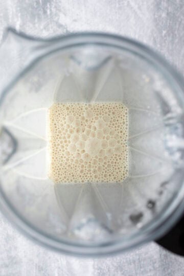 Creamy mixture inside a blender made with almond milk and cashews.