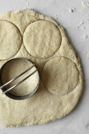 Using a round cutter to cut the biscuits.