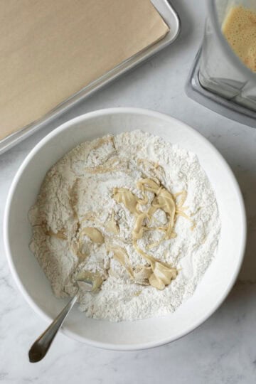 Using a fork to cut white almond butter into the flour mixture.