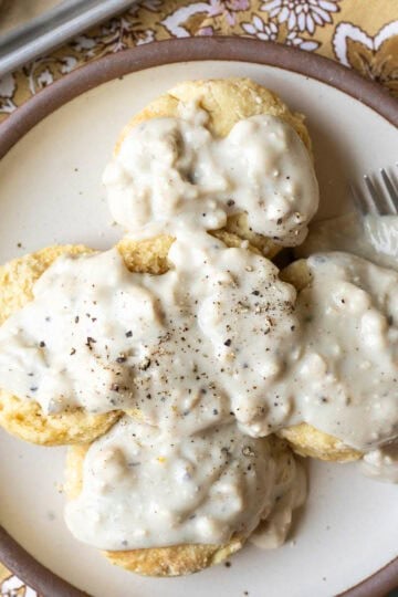 A plate of vegan biscuits smothered with white country gravy.