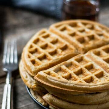 A few waffles stacked on a plate.