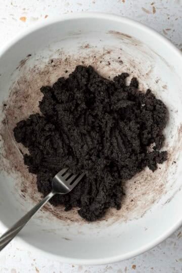 Using a fork to mix the cookie dough in a large bowl.