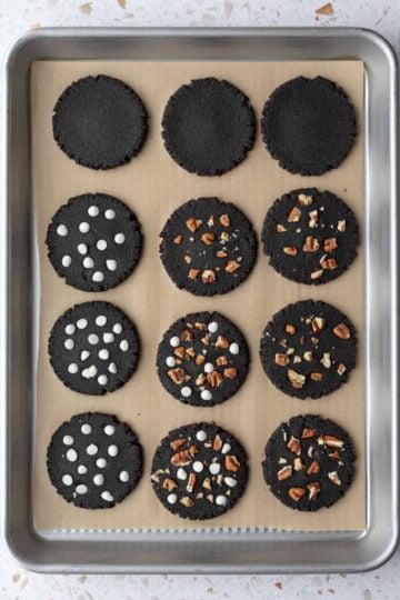 Unbaked cookies with chocolate chips and pecans pressed into the tops.