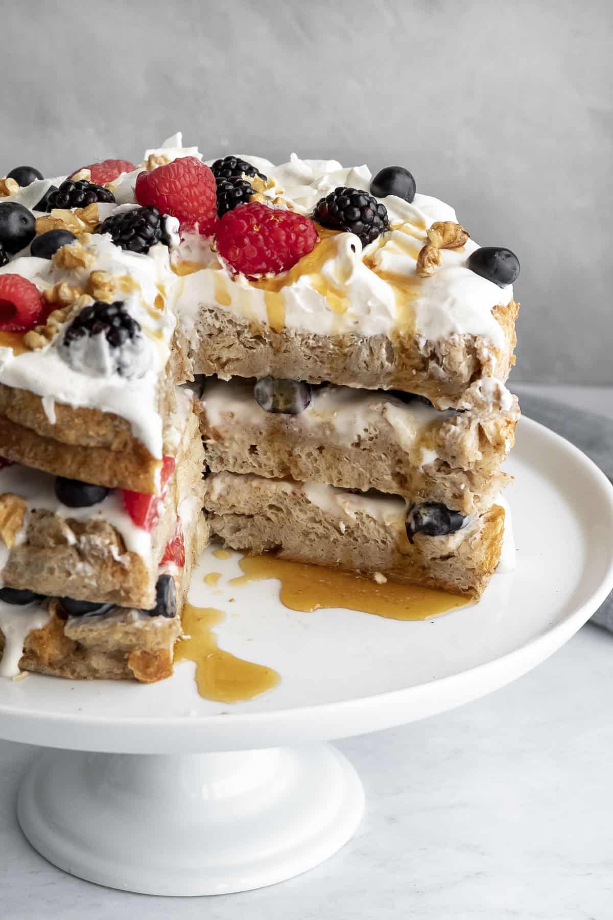 Decorated breakfast cake with slices removed to show the inside texture and layers of yogurt and berries.