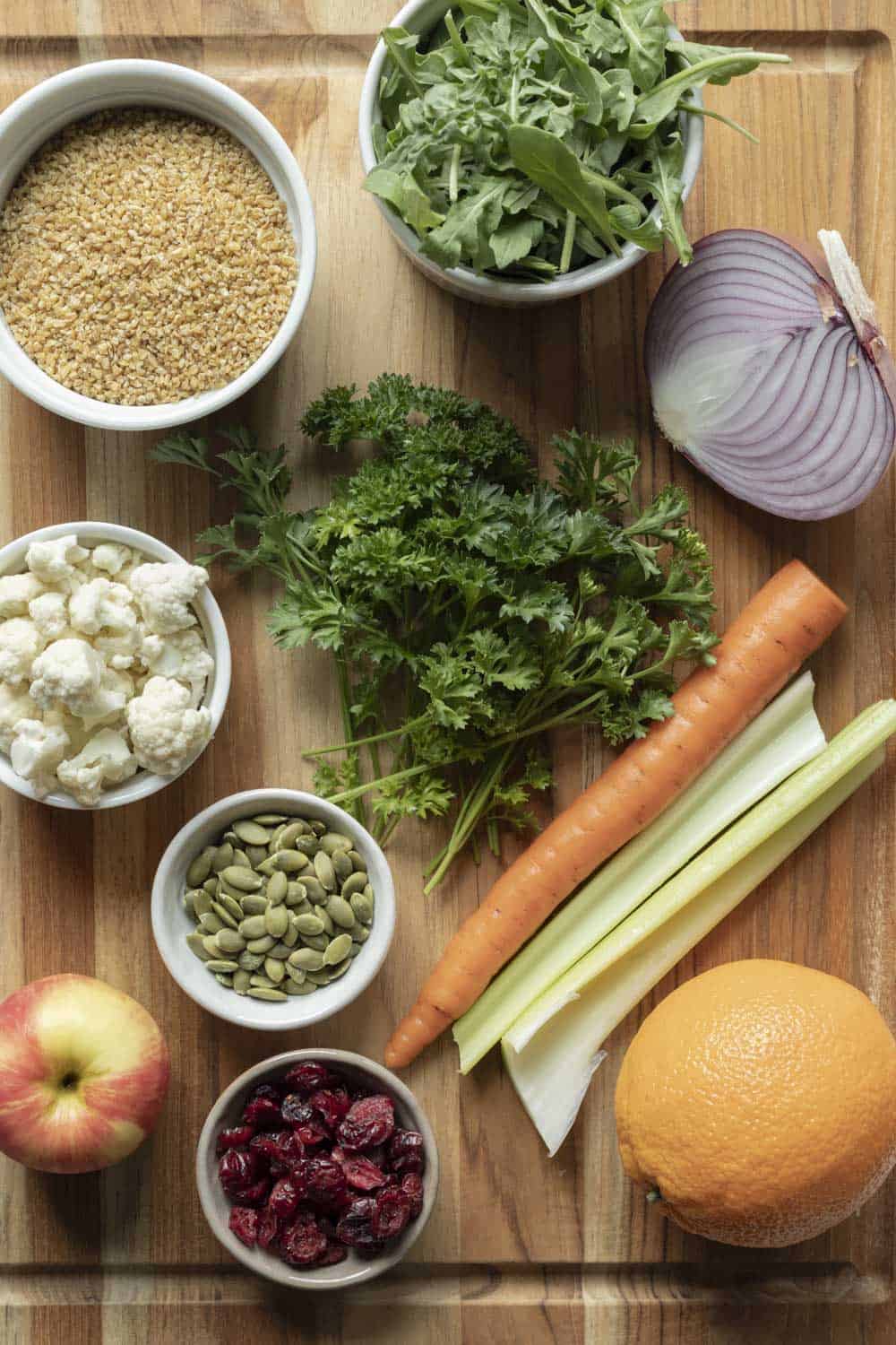Ingredients for bulgur salad on a wood cutting board.