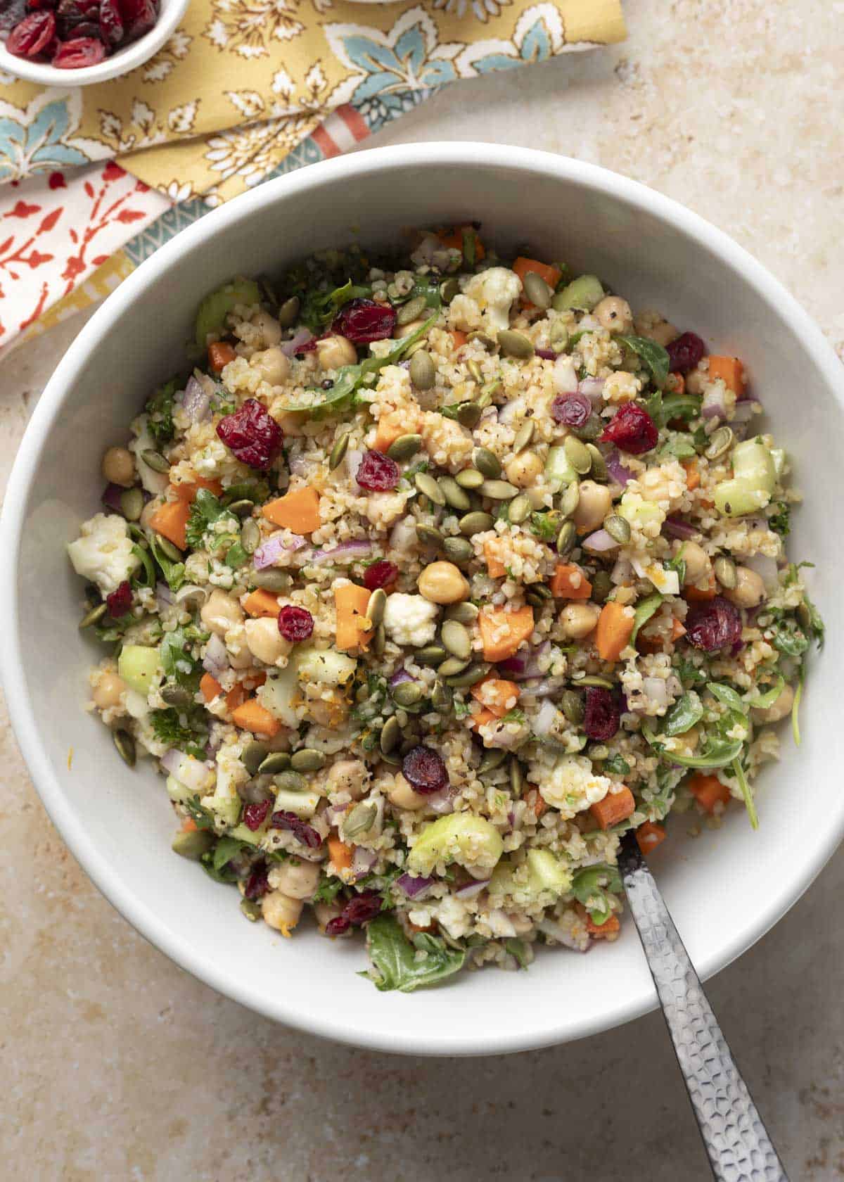 Fresh autumn bulgur salad in a large serving bowl with a spoon.