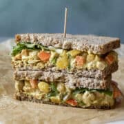 Two halves of curry chickpea salad sandwich stacked.