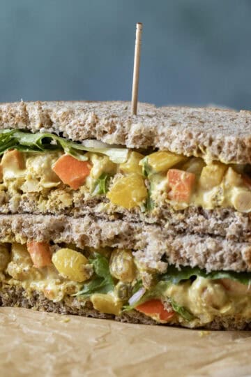 Two halves of curry chickpea salad sandwich stacked.