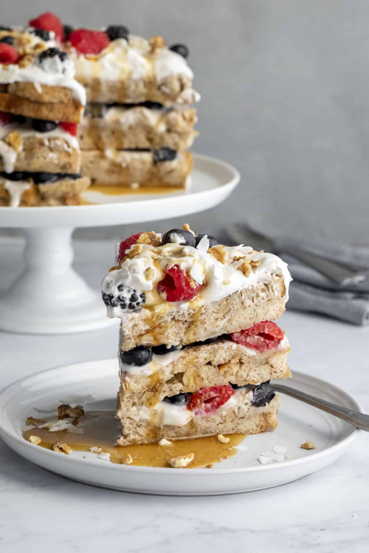 A slice of 3-layer baked french toast with berries, yogurt, and coconut whipped cream.