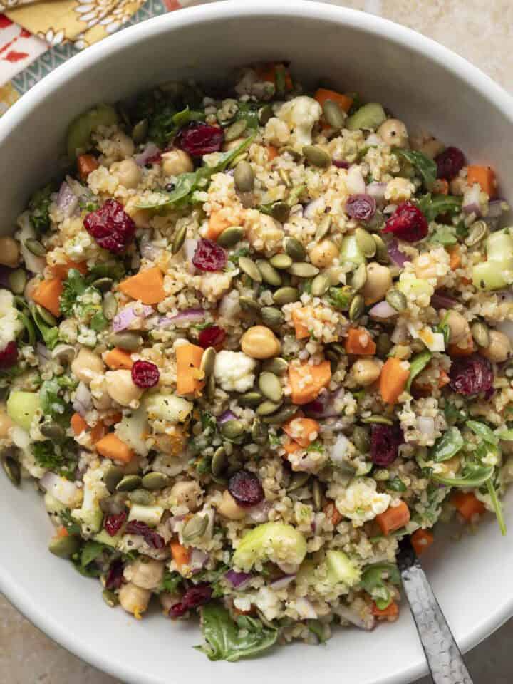 Overhead view of colorful autumn bulgur salad in a white serving bowl.