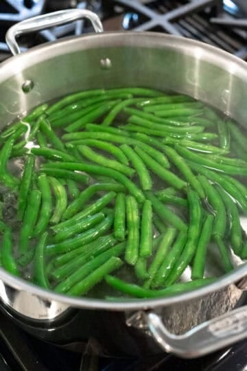 Briefly cooking fresh green beans in water.