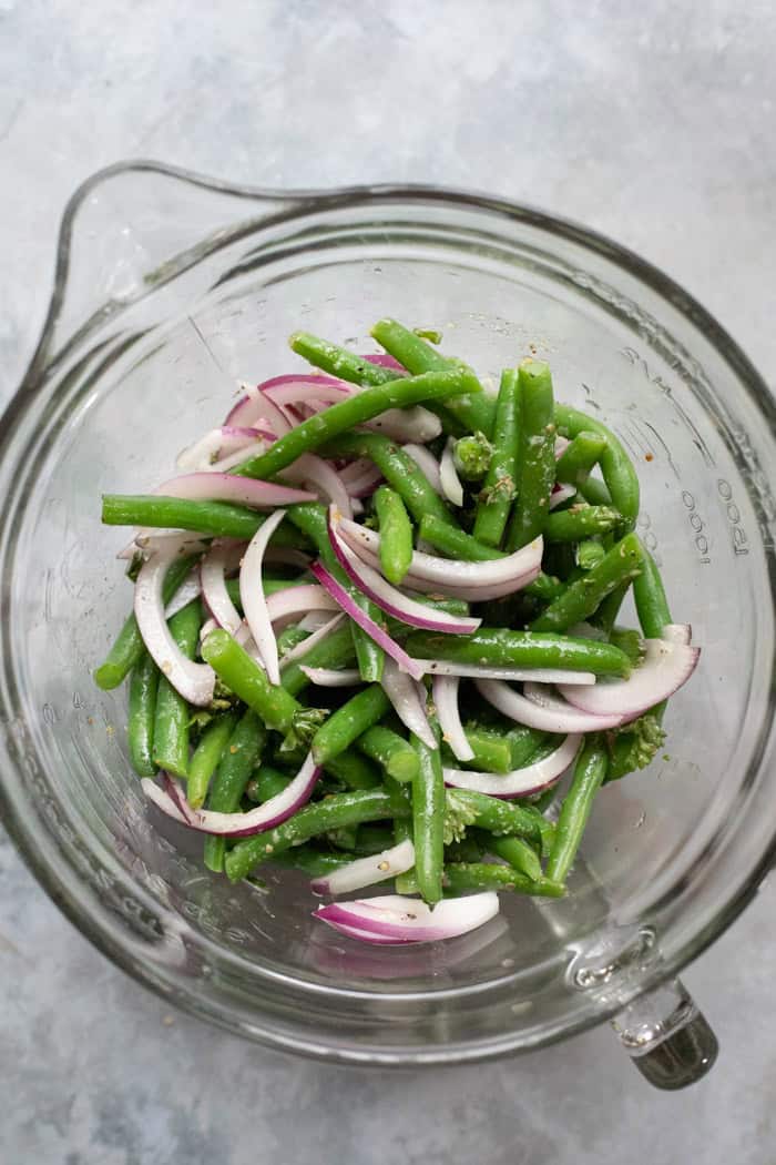 Tossing the green beans with Italian salad dressing.