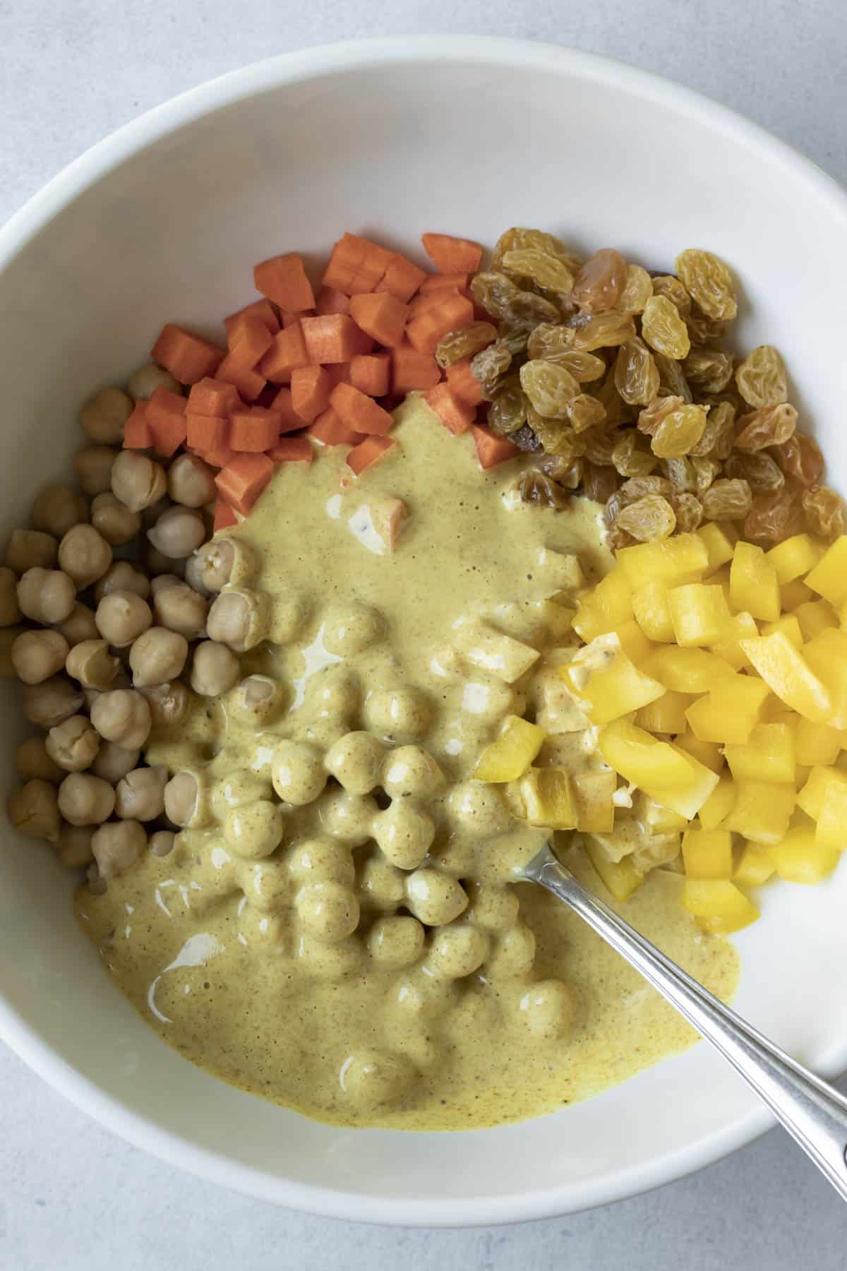 All ingredients for curry chickpea salad in a large bowl ready to be mashed.