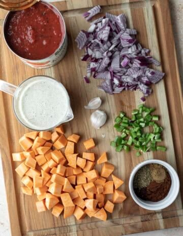 Chopped and prepped ingredients for vegetarian sweet potato chili laid out on a cutting board.