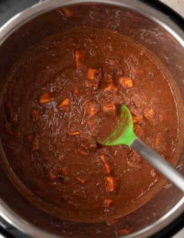 Adding crushed tomatoes and the secret ingredient walnut milk mixture to the Instant Pot.