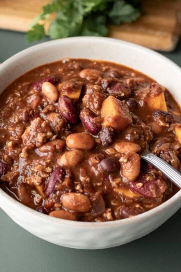 A bowl of thick vegan chili made with sweet potato, beans, and lentils.