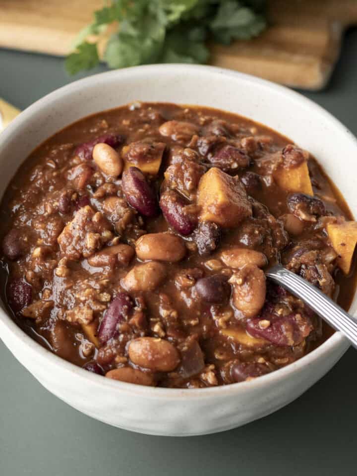 A bowl of thick vegan chili made with sweet potato, beans, and lentils.
