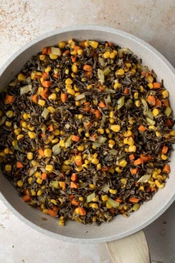 Cooked wild rice added to the pan with the sauteed vegetables and herbs.