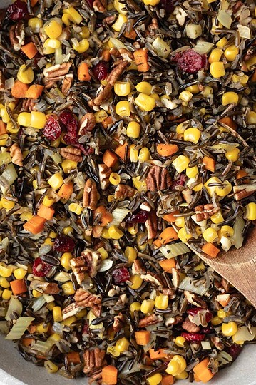 Wild rice with corn, cranberries, and other vegetables in a large pan.