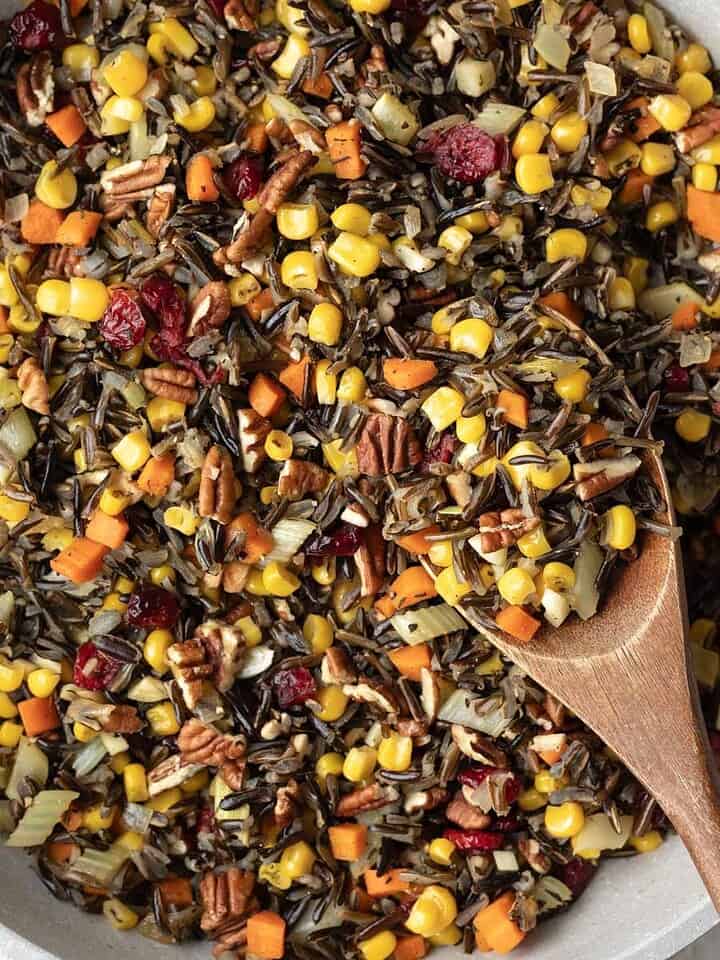 Wild rice with corn, cranberries, and other vegetables in a large pan.