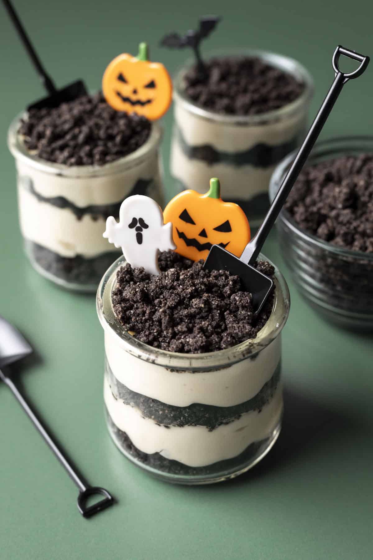 Small glasses filled with layered homemade vegan dirt cake and decorated for Halloween.