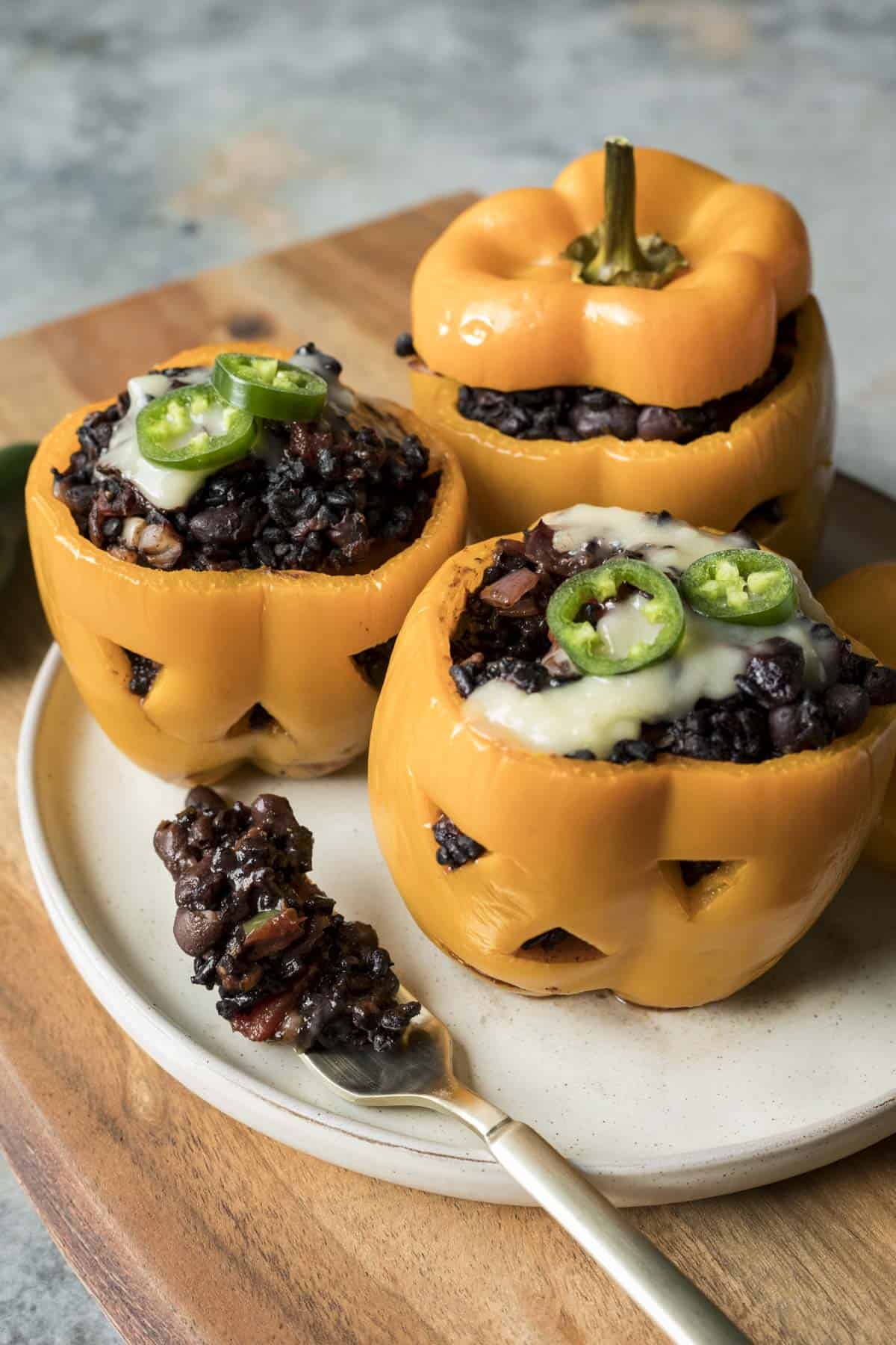 Stuffed peppers and a fork full of the black bean and black rice filling resting on a plate.