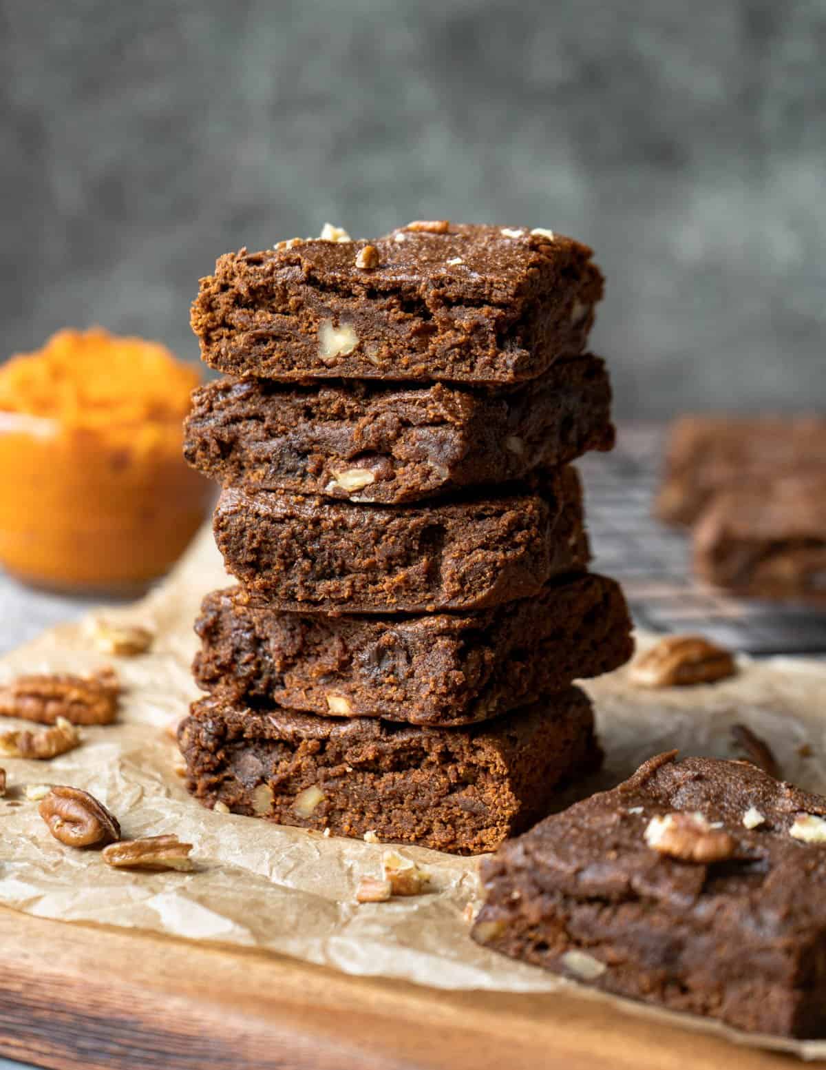 A stack of healthy pumpkin brownies against a dark background.