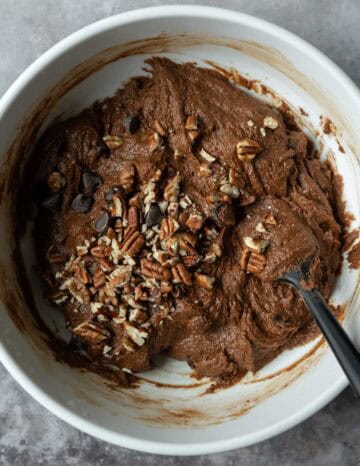 Folding chocolate chips and chopped pecans into the batter.