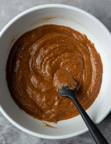 Stirring together pumpkin puree, almond butter, maple syrup, vanilla, and pumpkin pie spice.
