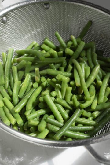 Draining green beans in a colander.