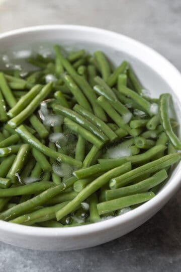 Freshly cooked green beans chilling in an ice bath.