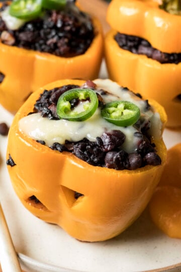 Stuffed orange bell peppers carved like pumpkins and filled with black rice and beans.