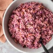 Overhead view of pink cranberry coleslaw in a white serving bowl.