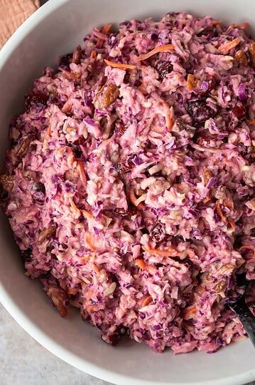 Overhead view of pink cranberry coleslaw in a white serving bowl.