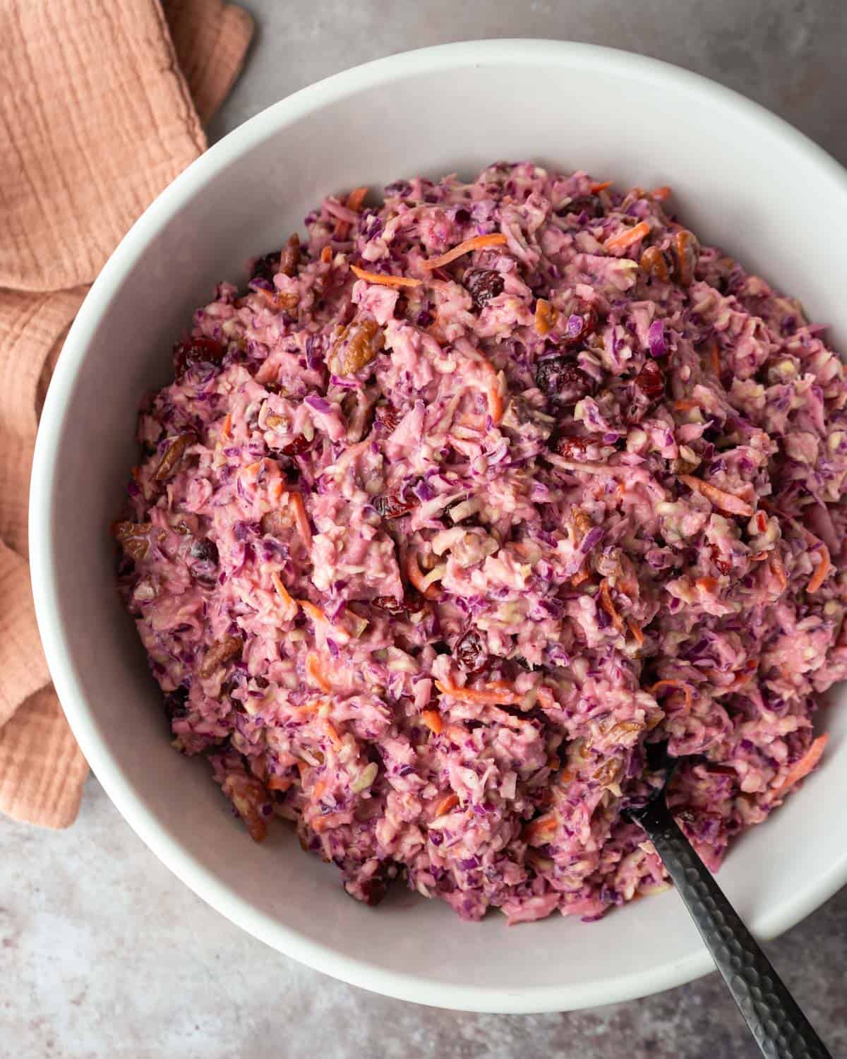 A serving bowl filled with brightly colored fresh cranberry coleslaw.