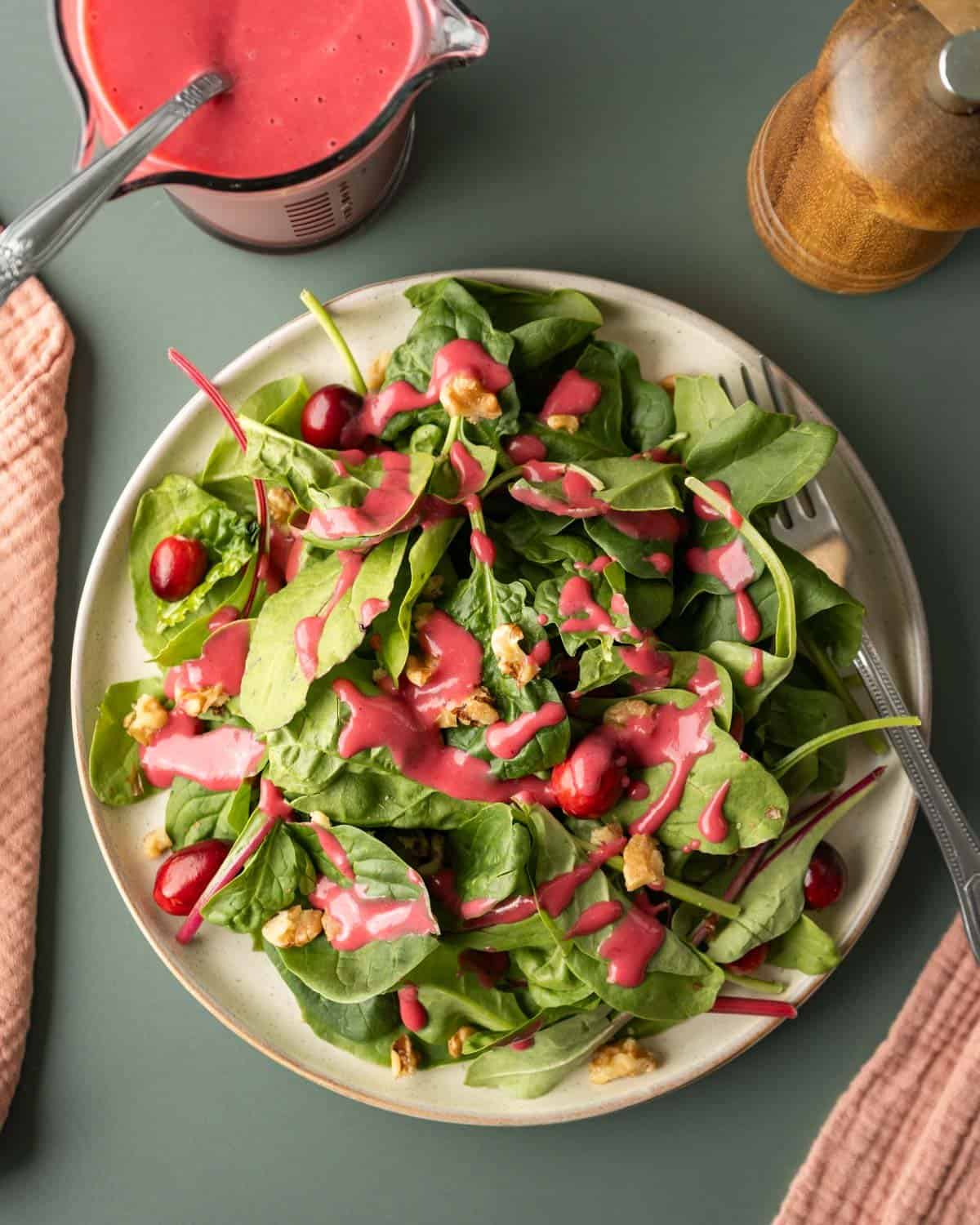 A mixed greens salad dressed with colorful cranberry dressing.